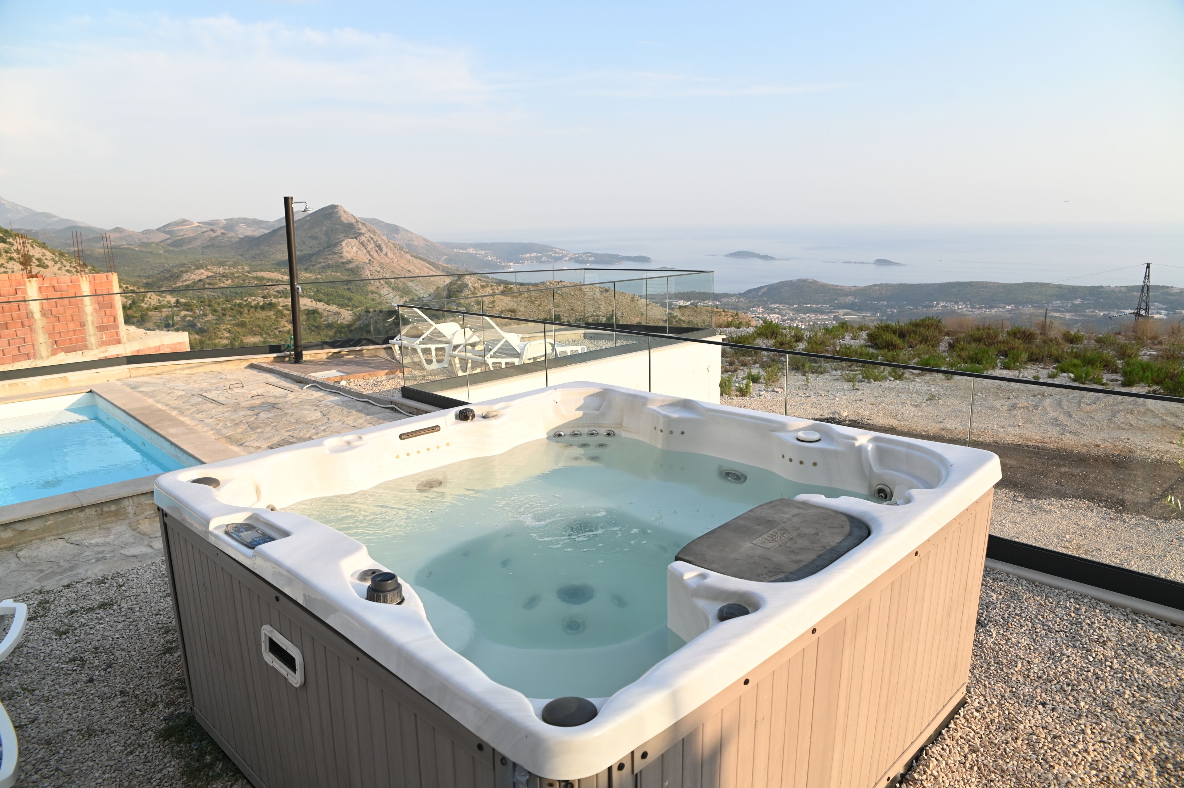 Ein Whirlpool auf einem Dach mit Pool und Blick auf das Meer und die Berge.