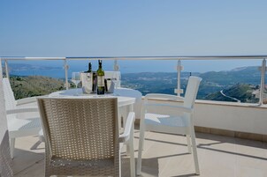 A terrace with a table and chairs, a bottle of wine, and a glass.