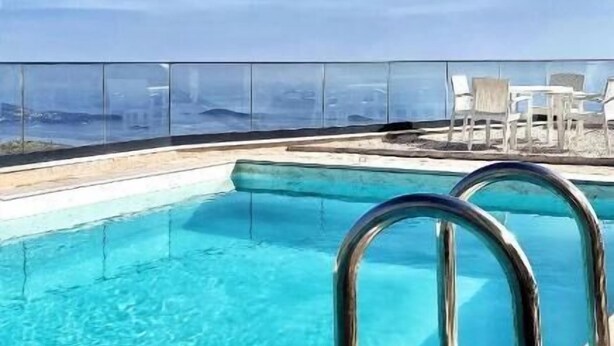 A clear blue pool with metal railings, surrounded by lounge chairs and a view of the ocean. - Dubrovnik Heights Luxury Villa (Ravno)