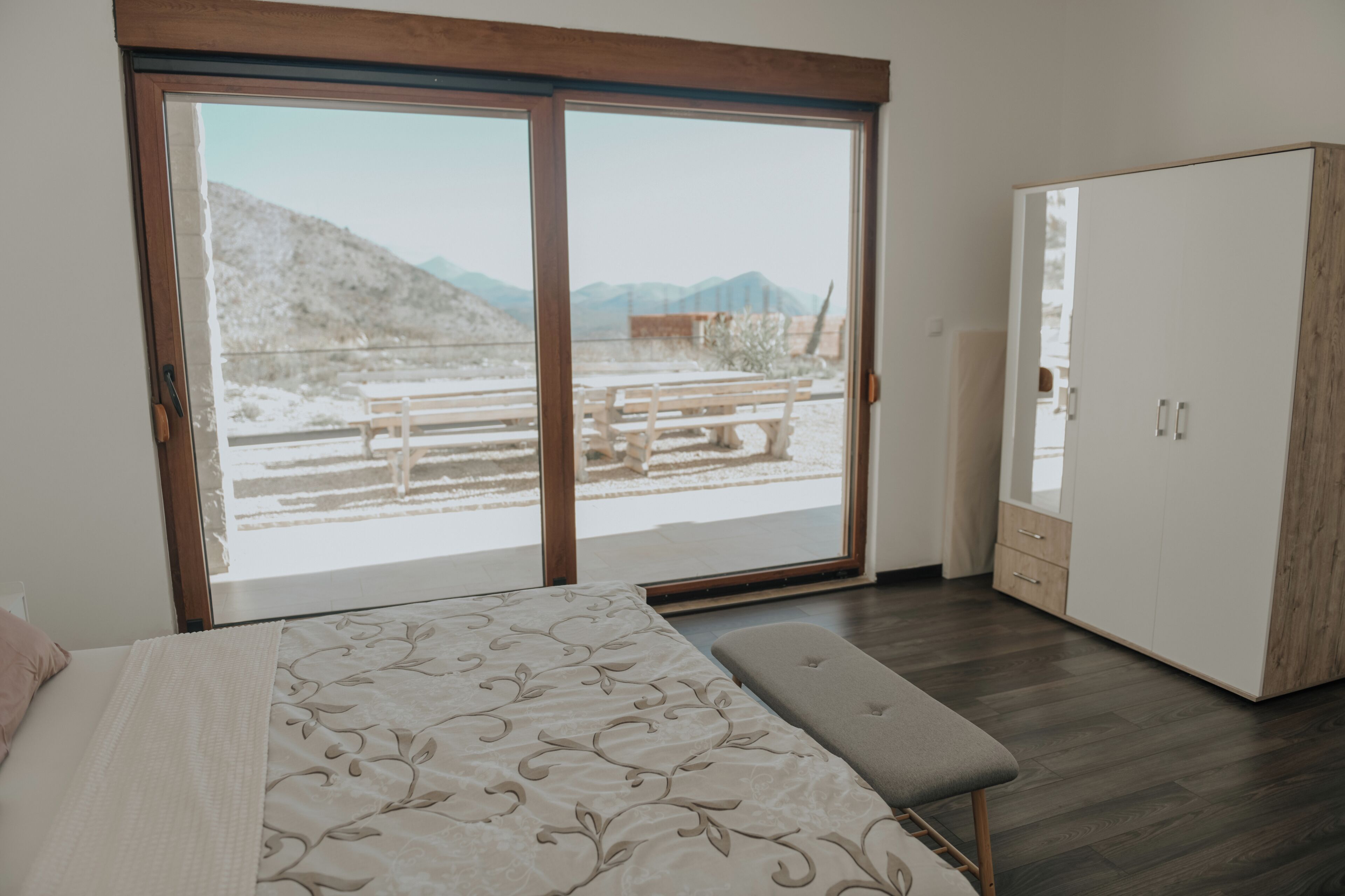 A bedroom with a bed, bench, and a wardrobe.