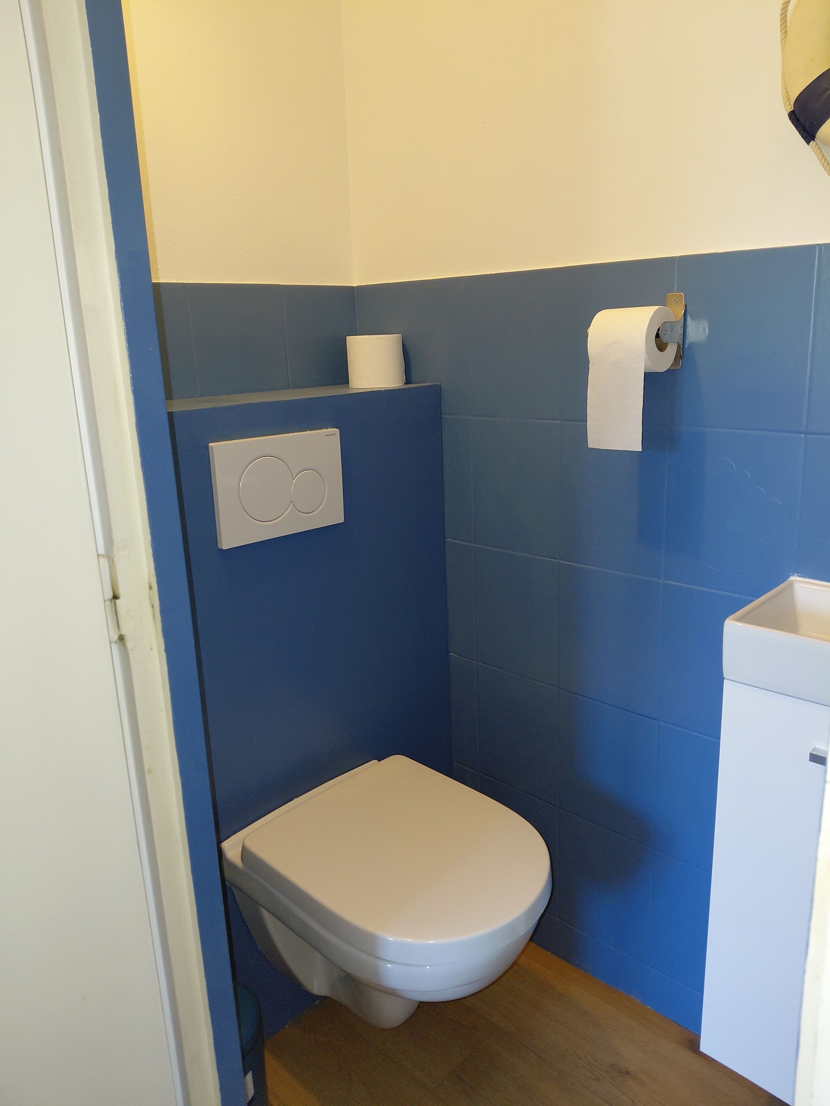 Un baño pequeño con un inodoro blanco, un dispensador de toallas de papel y un porta papel higiénico en la pared.