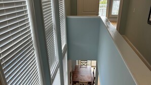 Una escalera de madera con detalles blancos que conduce a un comedor con mesa y sillas.