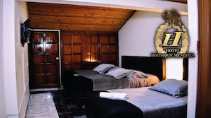 A hotel room with two beds, a wooden ceiling, and a large emblem on the wall. - Hotel Boutique Mendoza (Bogotá)