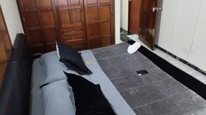 Une chambre à coucher avec un lit, une armoire en bois et un sol carrelé.