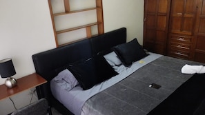 A bed with a dark headboard, a grey blanket, and two black pillows. - Hotel Boutique Mendoza (Bogotá)