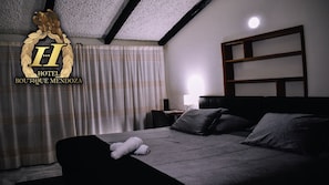 A hotel room with a bed, pillows, a nightstand, a lamp, and a window with curtains. - Hotel Boutique Mendoza (Bogotá)