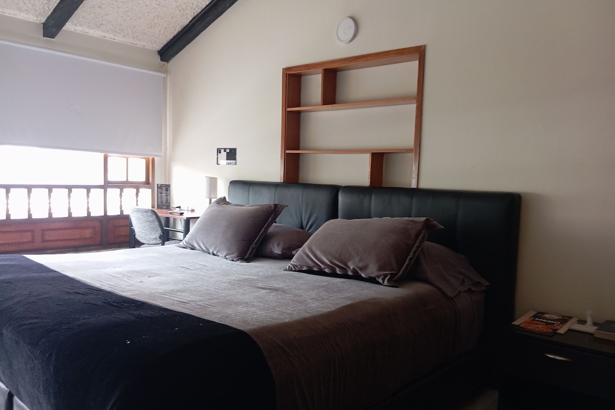 A bed with a headboard, pillows, a bedside table, and a nightstand.