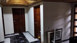 A hallway with two wooden doors, a fire extinguisher, and a chair. - Hotel Boutique Mendoza (Bogotá)