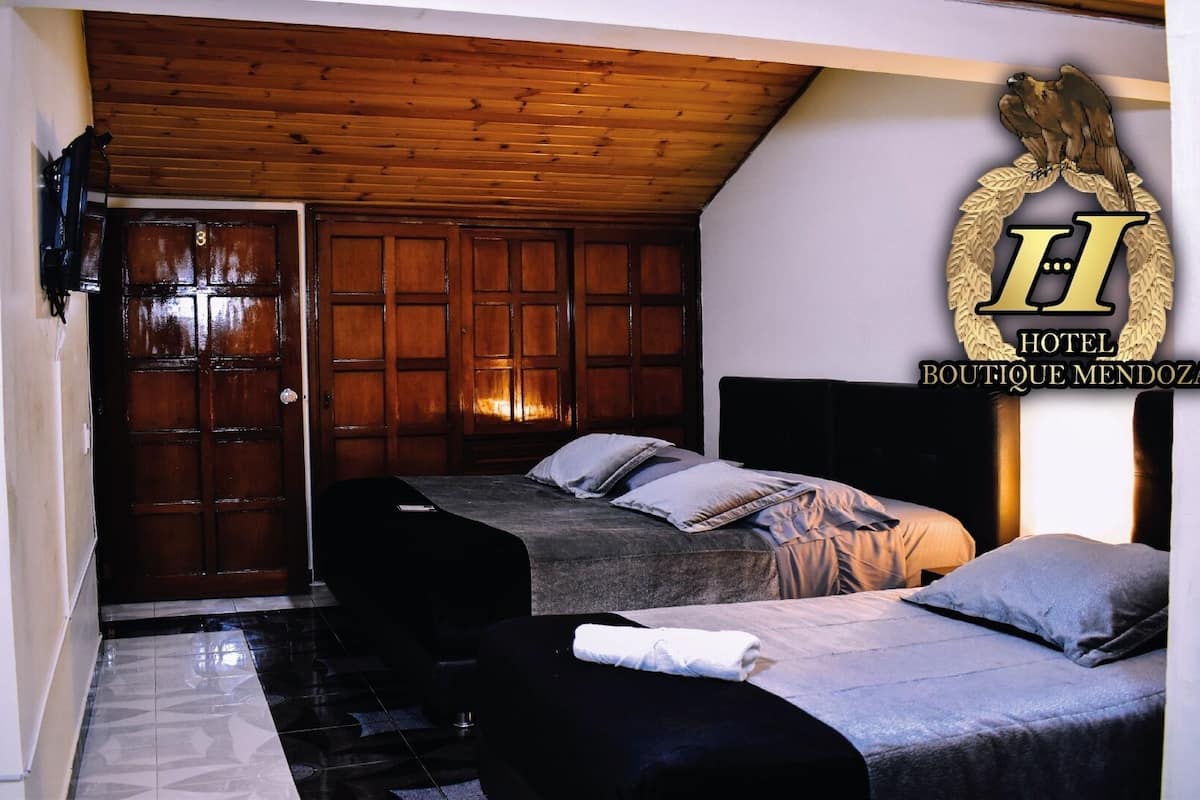 A hotel room with two beds, a wooden ceiling, and a large emblem on the wall.