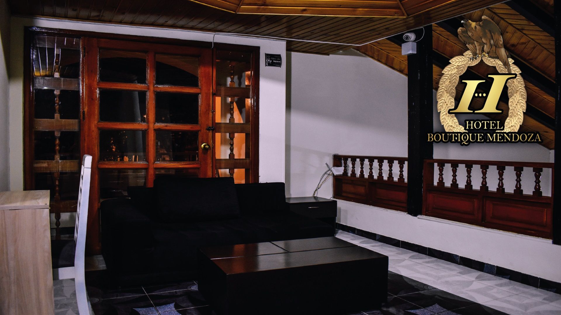 Eine Hotelhalle mit einem Holzbuchttisch, einem schwarzen Sofa und einem großen Hotelwappen.