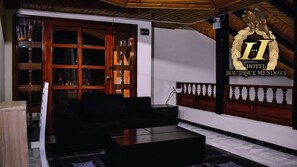Un hall d’hôtel avec un comptoir d’accueil en bois, un canapé noir et un grand emblème de l’hôtel.