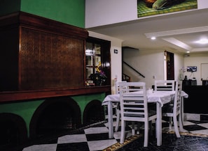 A dining area with a checkered floor, white chairs, and a table. - Hotel Boutique Mendoza (Bogotá)