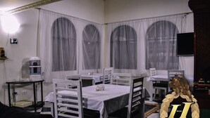 Una habitación con paredes blancas, un cuadro, un dispensador de agua y mesas con sillas.