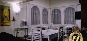 A room with white walls, a painting, a water dispenser, and tables with chairs. - Hotel Boutique Mendoza (Bogotá)