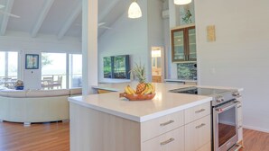 A modern kitchen with a central island, wooden cabinets, and a built-in oven. - Tropical & Elegant- Sleeps 8- Ocean/Waterfall Views (Princeville)