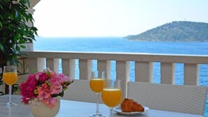 A table with a flower vase, two glasses of orange juice, a croissant, and a plate with a croissant. - Apartment Marina by Interhome (Rogoznica/Ražanj)