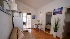 A living room with a beige sofa, a dining area with a table and chairs, and a kitchen area with a refrigerator. - Apartment Marina by Interhome (Rogoznica/Ražanj)