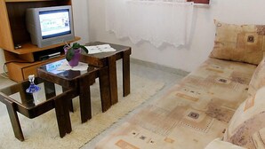 A living room with a sofa, a coffee table, a television on a wooden stand, and a small plant on the coffee table. - Margita by Interhome (Brač/Supetar)