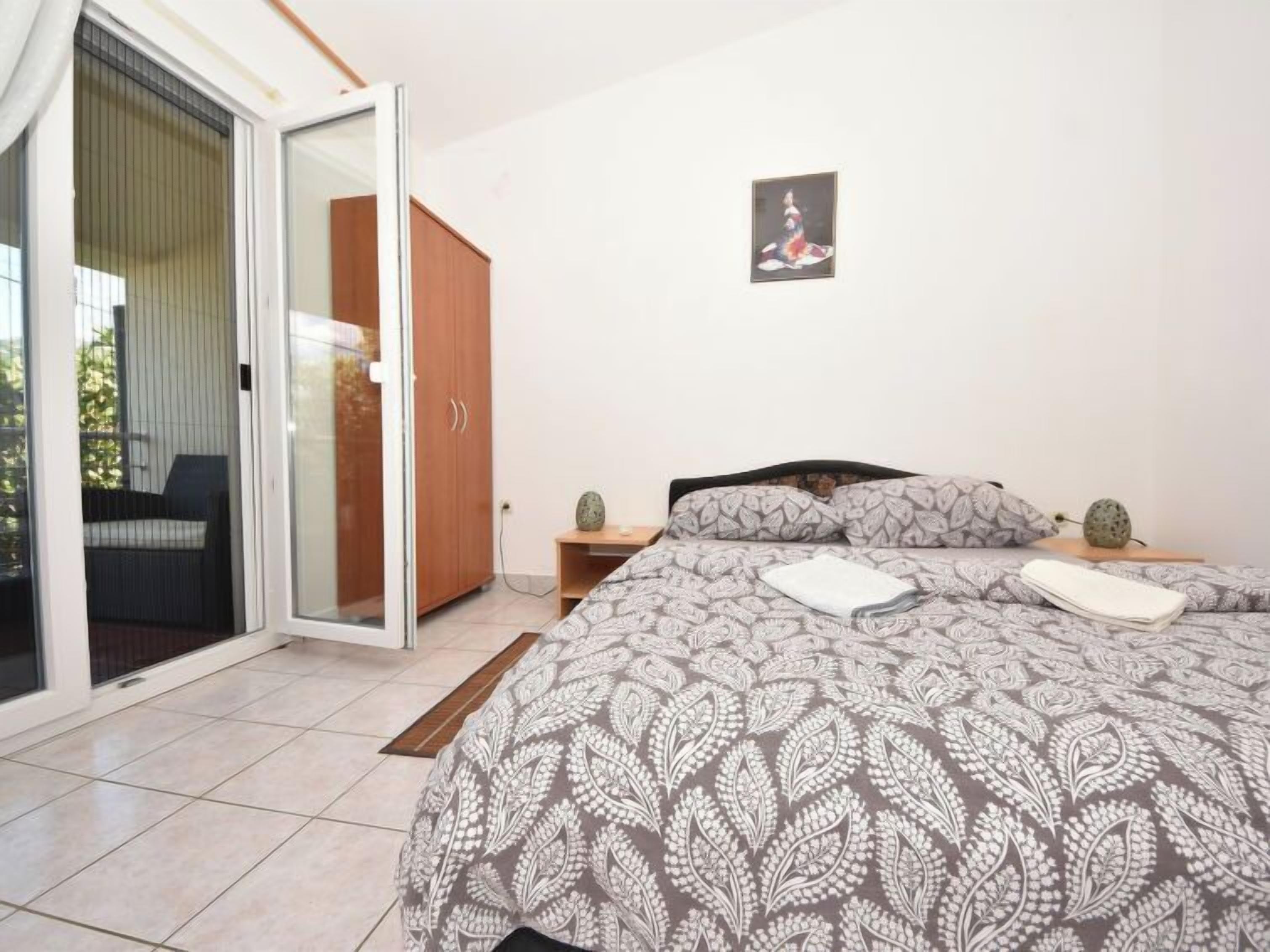 A bedroom with a bed, a wardrobe, a small table with a fruit, and a picture on the wall.