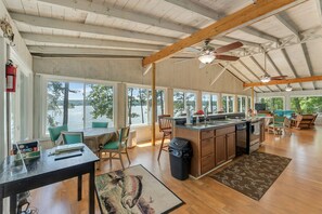 Une cuisine spacieuse, dotée de grandes fenêtres, de poutres en bois et offrant une vue sur le lac.