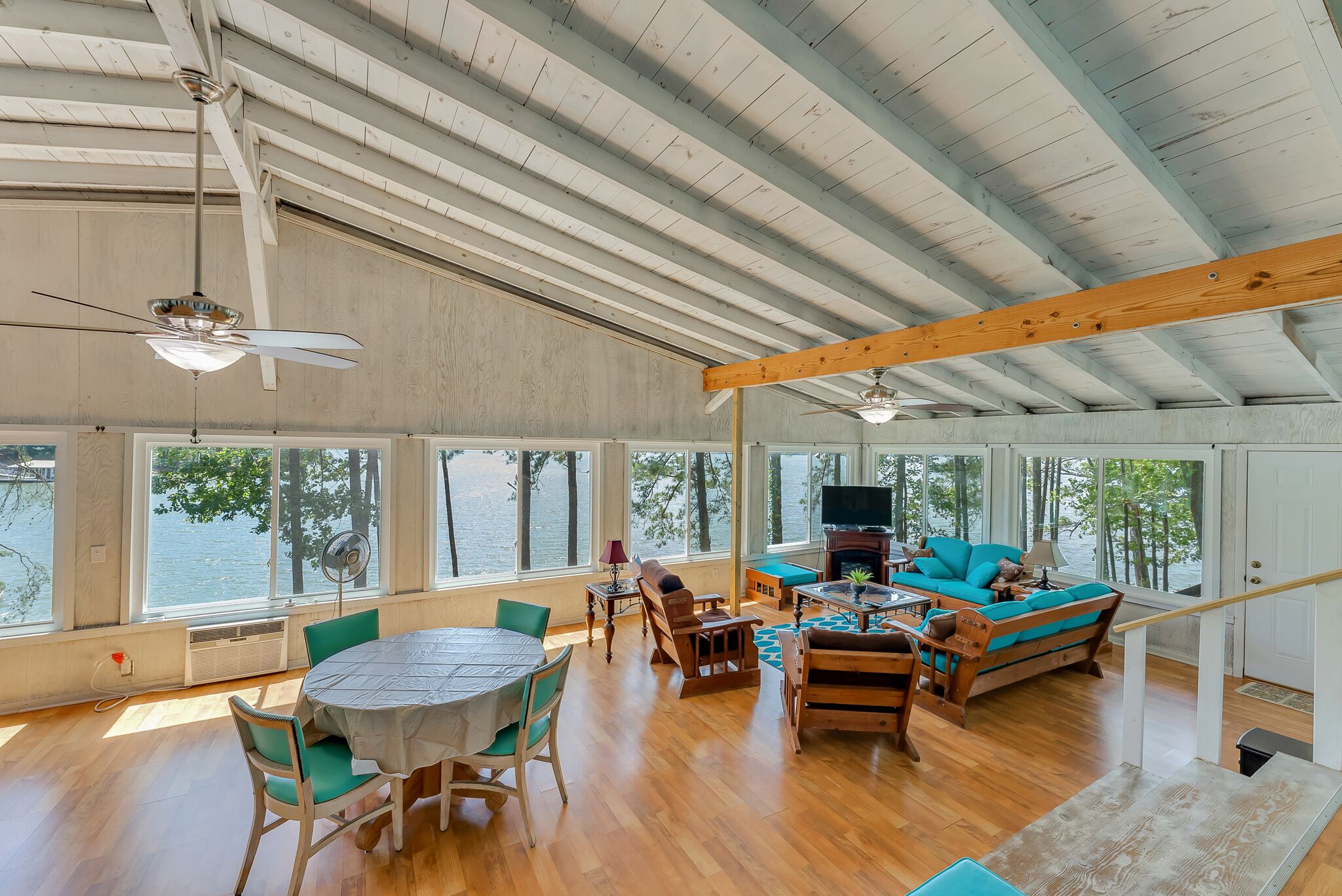 A spacious living area with a high ceiling, large windows, and a view of the water.