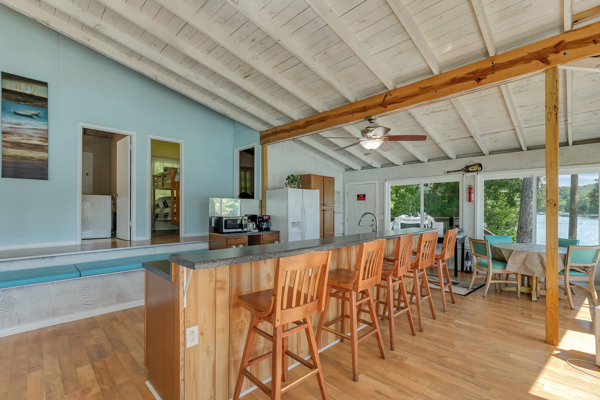 A spacious kitchen with a wooden bar area, a ceiling fan, and a view of the outdoors.