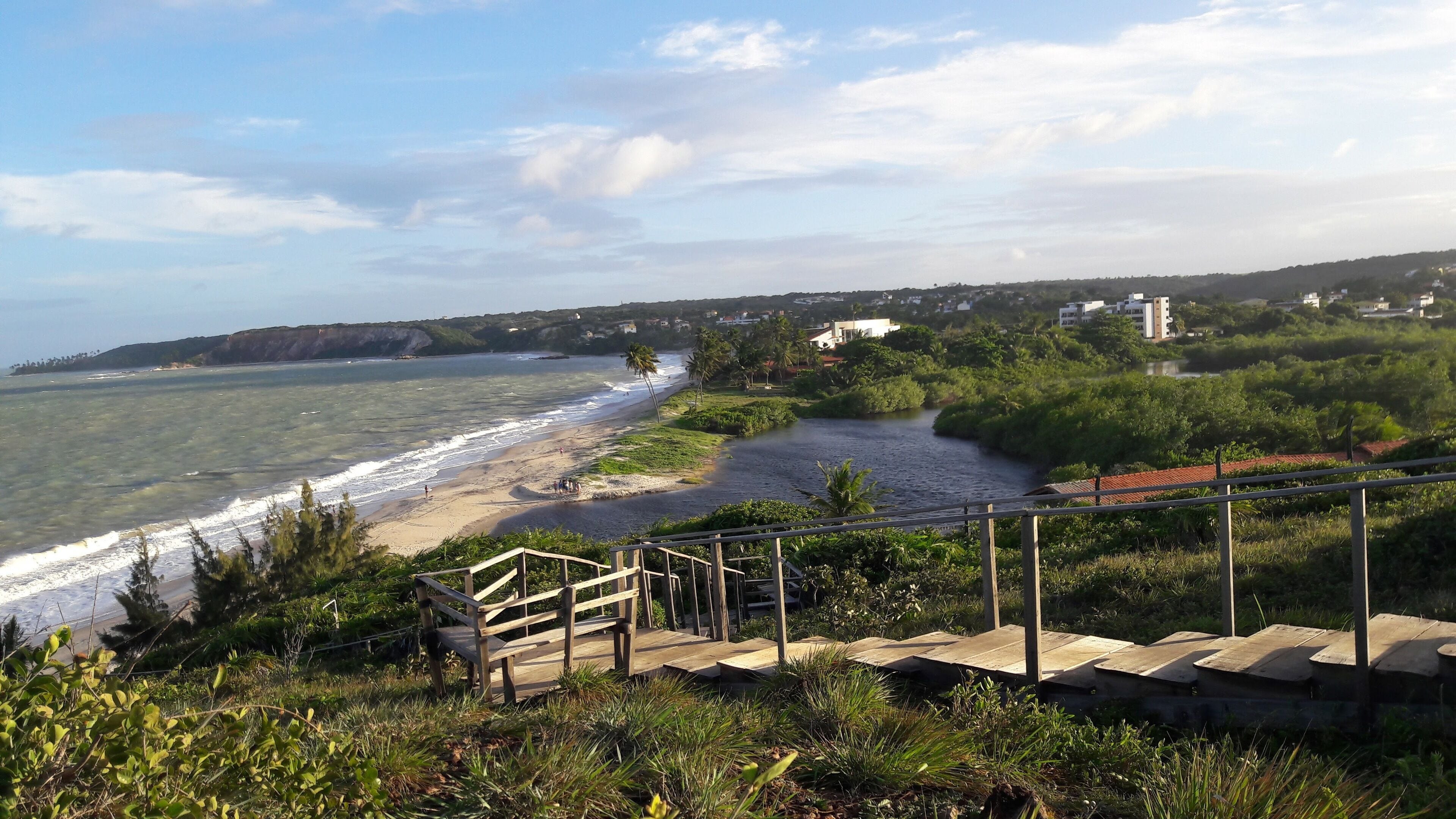 A coastal landscape with a beach, a river, and a staircase leading down to the beach.