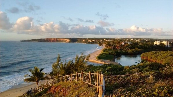 A coastal view with a beach, a river, and a forested area. - Pousada Laguna (Conde)