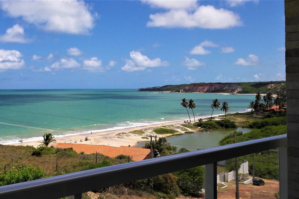 A coastal view with a beach, palm trees, and a clear sky.