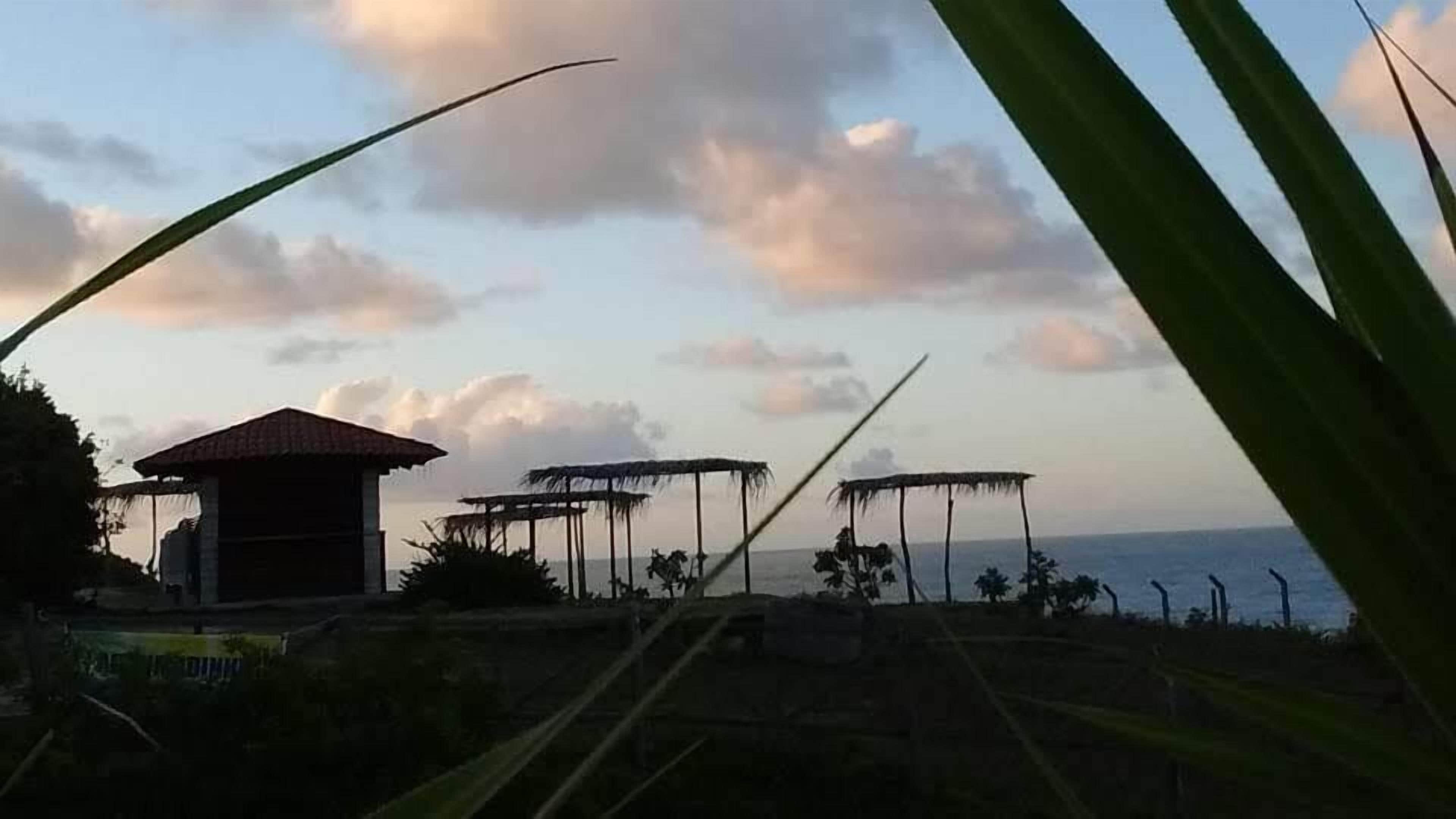 Paesaggio costiero con edifici a tetti di paglia e un edificio con tetto in tegole.