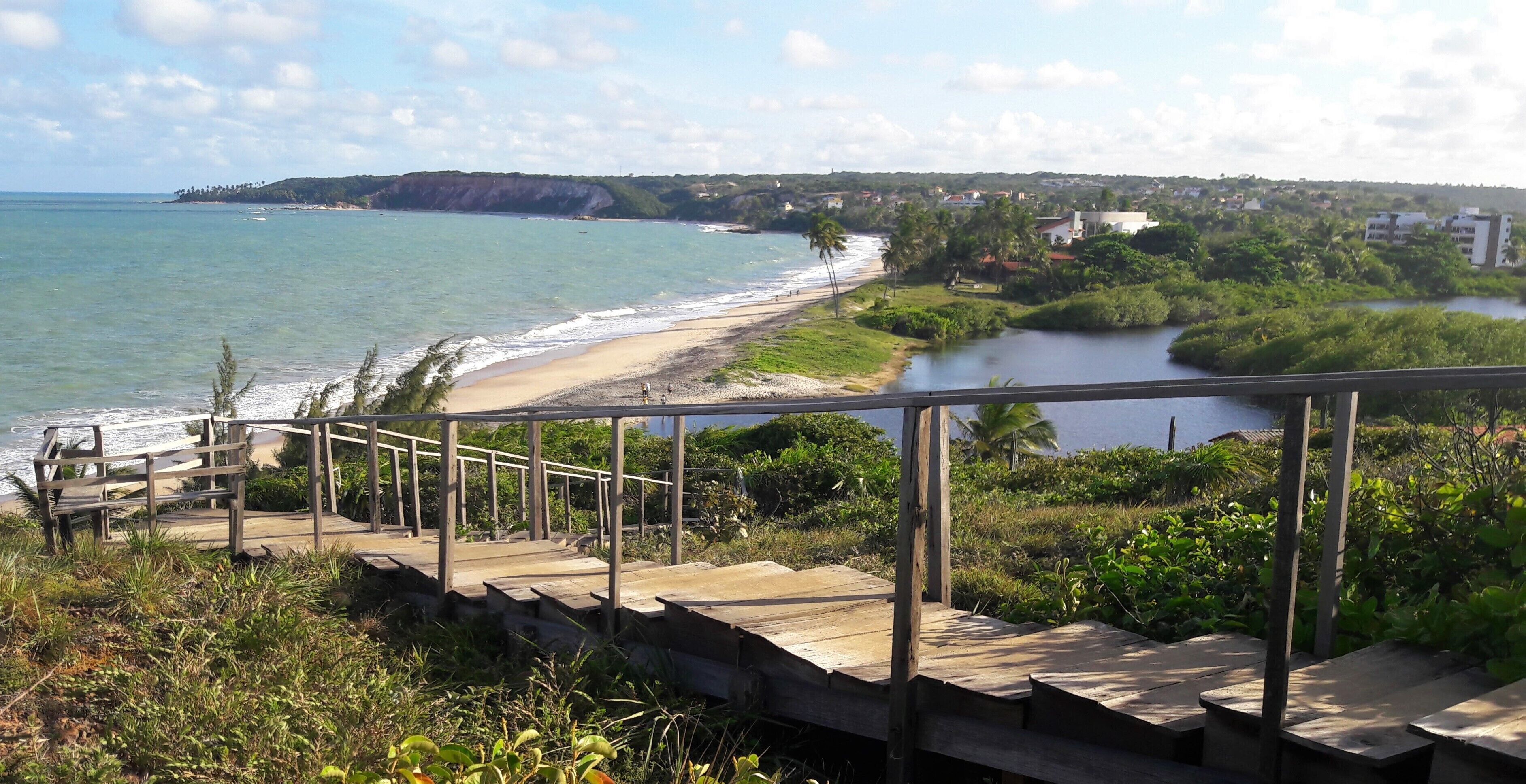 A coastal view with a wooden staircase leading to a beach.