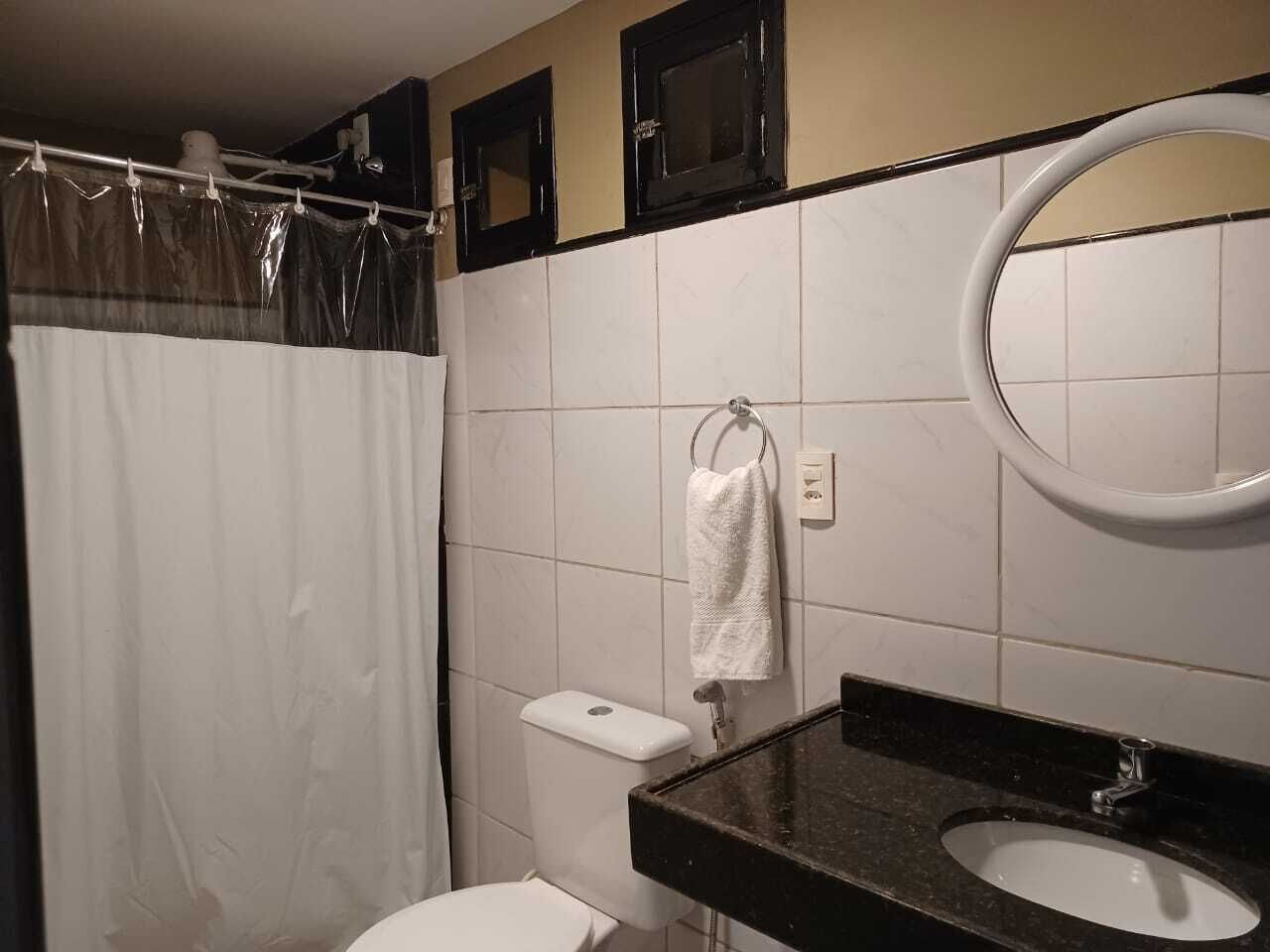 A bathroom with a toilet, a sink, a mirror, and a shower curtain.