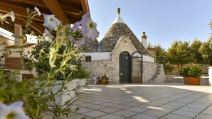 A stone building with a green door and a tiled patio area. - Stylish Trulli with Private Pool for 4 guests in Puglia (Castellana Grotte)