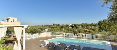 Una piscina al aire libre, sillones reclinables de piscina