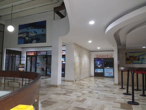 A spacious lobby with a tiled floor, a central column, and a restaurant named "Ravanderia" in the background.