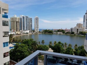 A high-rise building with a view of a lake and surrounding greenery.