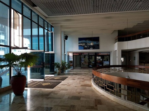 Un vestíbulo amplio con grandes ventanales, una escalera central y un diseño moderno.