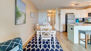 Una cucina moderna con mobili bianchi, un'isola centrale e un'area pranzo con un tappeto decorativo.