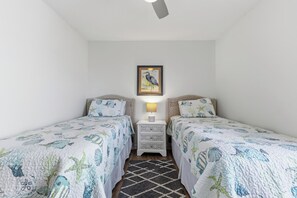 A room with two single beds, a nightstand with a lamp, and a framed picture on the wall.