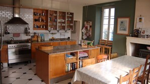 Una cocina con una isla central, armarios de madera, una estufa y un comedor con mesa y sillas.