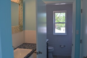 Un baño con bañera, inodoro y ventana.