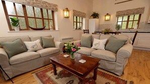 A living room with two beige sofas, a wooden coffee table, and a patterned rug.