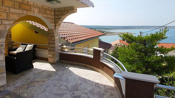 Un balcon doté d’un sol en pierre, d’un mur jaune et offrant une vue sur la mer.