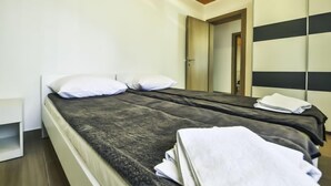 Une chambre d’hôtel moderne, équipée d’un lit, d’une armoire et d’une porte donnant sur une autre pièce.