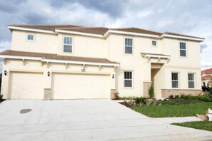 Stunning two-story home with a central entrance, flanked by garages, set amidst a beautifully manicured lawn.