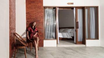 A room with a bed, a chair, and a sliding door to a balcony.
