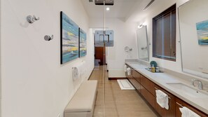 Ein modernes Badezimmer mit einem langen Waschtisch, zwei Spiegeln und Bildern an den Wänden.