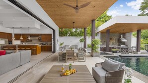 Un espacio exterior moderno con piscina, comedor y cocina.