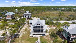 A coastal property with multiple buildings, including a large house with a balcony and a smaller structure nearby. - Baydream: Stunning Bayfront Home, Pet-Friendly, Hot Tub, Sleeps 12 (Port St. Joe)