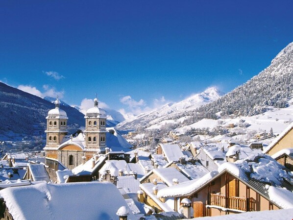 Un pueblo cubierto de nieve con edificios tradicionales y una iglesia destacada con dos torres.